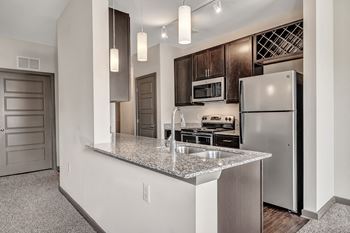 A kitchen with a granite countertop and stainless steel appliances.